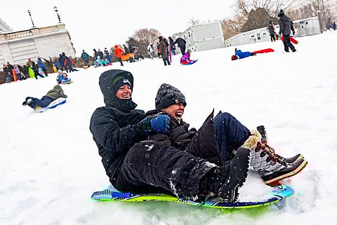 People sled down the hill on the west front of the US Capitol on January 25, 2026 in Washington, DC. A massive winter storm is expected to bring frigid temperatures, ice, and snow to millions of Americans across the nation.