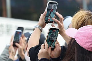 Onlookers use their phones to record footage