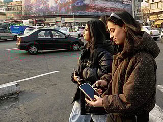 Two girls walk past a billboard at Enqelab-e-Eslami (Islamic Revolution) Square in Tehran, on Sunday.