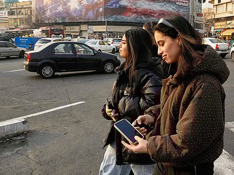 Two girls walk past a billboard at Enqelab-e-Eslami (Islamic Revolution) Square in Tehran, on Sunday.