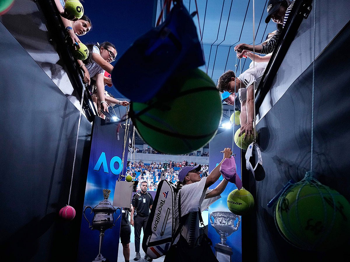 Iga Swiatek of Poland signs autographs after defeating Anna Kalinskaya of Russia in their third round match at the Australian Open tennis championship in Melbourne, Australia.