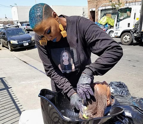 This photo provided by Melissa Acedera shows Shirley Raines washing a person's hair in Skid Row, 2018, in Los Angeles. (Melissa Acedera via AP)