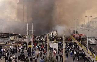 People stand and watch as firefighters battle a fire that broke out in Jannat Bazaar, west of Tehran on February 3, 2026. 