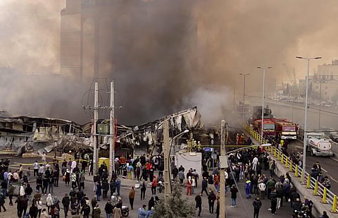 People stand and watch as firefighters battle a fire that broke out in Jannat Bazaar, west of Tehran on February 3, 2026. 