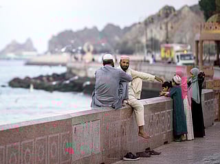 Two men sit along the corniche in Oman's capital Muscat on February 5, 2026.