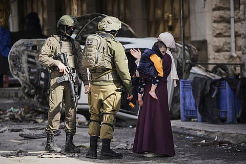 A Palestinian woman asks Israeli soldiers for access to her home during an army raid in the West Bank city of Hebron Monday, Jan. 19, 2026. (AP Photo/Mahmoud Illean)