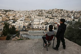 Palestinian boys look out over the Israeli-occupied West Bank city of Hebron from a rooftop on February 9, 2026.