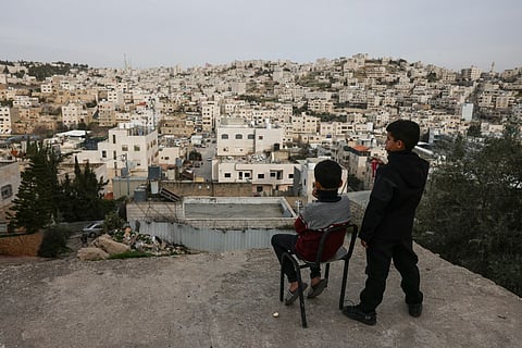 Palestinian boys look out over the Israeli-occupied West Bank city of Hebron from a rooftop on February 9, 2026.