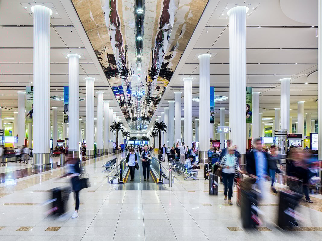 Interior view of Dubai International Airport Terminal 3 with passengers walking through the arrivals area.