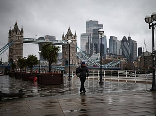 A pedestrian walks past Tower Bridge along the Thames in central London.