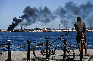 A man stares at black smoke billowing from a fire at the Nico Lopes oil refinery in Havana on February 13, 2026.