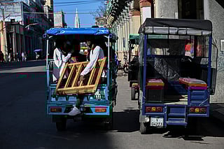 People ride an electric tricycle as another is parked on a street in Havana on February 13, 2026.