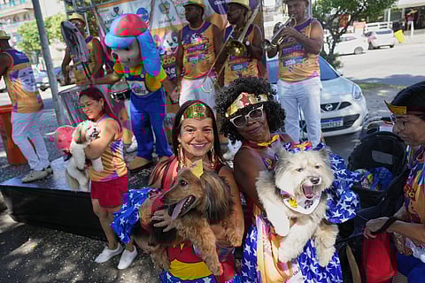 Owners and their pets pose for a photo at the "Blocao" Carnival dog parade in Rio de Janeiro, Saturday, Feb. 14, 2026. 