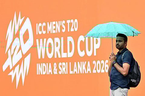 A cricket fan takes shelter under an umbrella as rain delays the start of the 2026 ICC Men's T20 Cricket World Cup group stage match between Zimbabwe and Ireland at Pallekele International Cricket Stadium in Kandy on February 17, 2026.