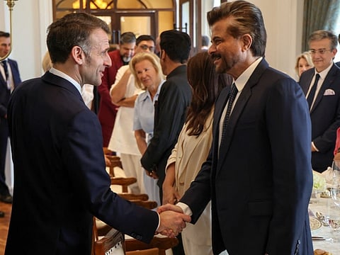 France's President Emmanuel Macron (L) shakes hands with Indian actor Anil Kapoor he attends a cinema-themed lunch with Bollywood stars and French artists in Mumbai on February 17, 2026.