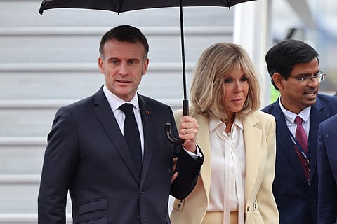 France's President Emmanuel Macron (L) and his wife Brigitte Macron (C) walk from their airplane as they arrive in New Delhi on February 18, 2026.