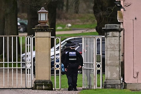 Police officers walk through the gated entrance to Royal Lodge, a 30-room property and former residence to Britain's former prince Andrew where police said they are still conducting a search, in Windsor, west of London on February 20, 2026, a day after Andrew Mountbatten-Windsor was arrested on the royal family's remote Sandringham estate in eastern England.