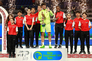 Spain's Carlos Alcaraz celebrates with the trophy after winning his men’s singles final match against France's Arthur Fils at the Qatar Open tennis tournament in Doha on February 21, 2026.