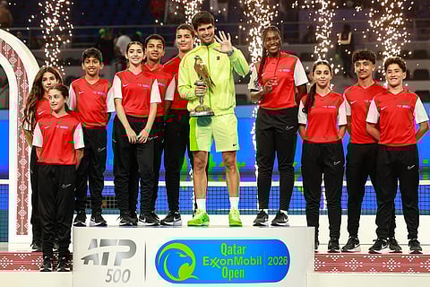 Spain's Carlos Alcaraz celebrates with the trophy after winning his men’s singles final match against France's Arthur Fils at the Qatar Open tennis tournament in Doha on February 21, 2026.