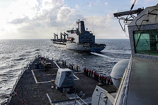 In this handout photograph released by the US Navy, the Arleigh Burke-class guided-missile destroyer USS Frank E. Petersen Jr. (DDG 121) sails alongside fleet replenishment oiler USNS Henry J. Kaiser (T-AO-187), during a replenishment-at-sea in the Arabian Sea on February 18, 2026.