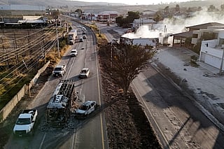This aerial view shows a burned bus and car, allegedly set on fire by organised crime groups in response to an operation to arrest a high-priority security target, on a highway near Acatlan de Juarez, Jalisco state, Mexico on February 22, 2026.