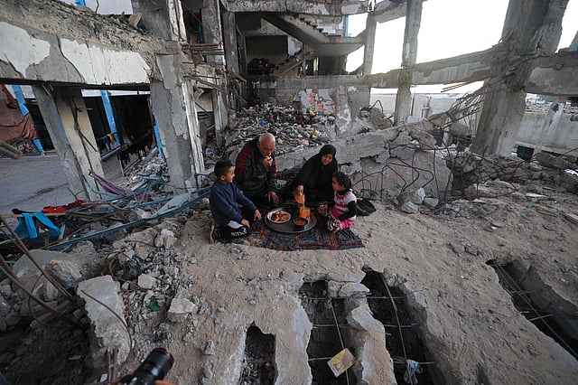 A displaced Palestinian family gather to sit for the "iftar" fast-breaking meal during the Muslim holy month of Ramadan, amidst the destruction in Bureij refugee camp in the central Gaza Strip.