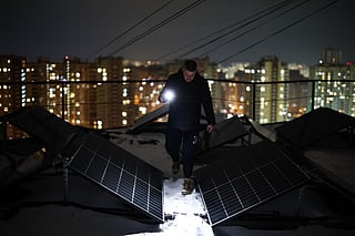Chairman of the Board of the Association of Co-Owners of the Apartment Building 'Dzherelo' Denys Biletsky, 42, inspects solar panels on the rooftop of a residential building, which has been suffering from heating and power outages, in the Pozniaky district of Kyiv on February 22, 2026, amid the Russian invasion of Ukraine.