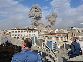 People watch as smoke rises on the skyline after an explosion in Tehran, Iran, on Saturday, February 28, 2026. 
