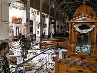 Sri Lankan security personnel walk past dead bodies covered with blankets amid blast debris at St. Anthony's Shrine following an explosion in the church in Kochchikade in Colombo on April 21, 2019. 