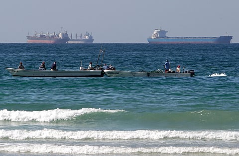 FILE - Fishermen work in front of oil tankers south of the Strait of Hormuz 