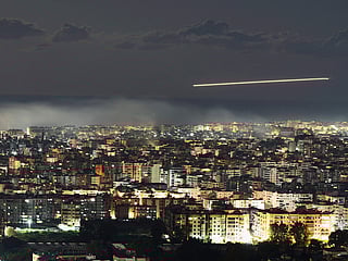 A Middle East Airlines plane flies over Beirut as smoke rises from Israeli airstrikes on Dahiyeh in Beirut's southern suburbs, early Monday, March 2, 2026.