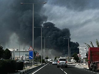 Motorists drive past a plume of smoke rising from a reported Iranian strike in the industrial district of Doha, Qatar, on March 1, 2026. 