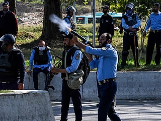 A riot policeman fires a tear gas shell towards protestors during their attempt to storm the US embassy in Islamabad.