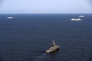 This handout picture provided by the Iranian Defence Ministry on March 12, 2024 shows (bottom) the Islamic Republic of Iran Navy frigate IRIS Dena (75) at sea during the "Maritime Security Belt 2024" combined naval exercise between Iran, Russia, and China in the Gulf of Oman.