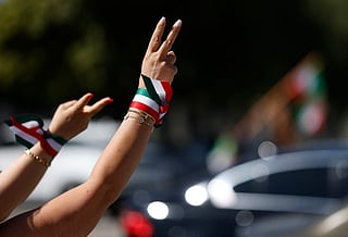 Demonstrators flash the peace sign in front of traffic during a rally in support of the war in Iran outside of the Wilshire Federal Building on March 07, 2026 in Los Angeles, California.