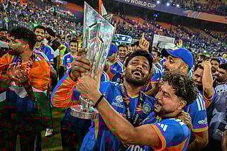 India's Sanju Samson (C) and Kuldeep Yadav (C, right) celebrate with the trophy during a victory lap after winning the 2026 ICC Men's T20 Cricket World Cup final match against New Zealand at the Narendra Modi Stadium in Ahmedabad on March 8, 2026.