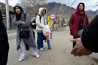Iranian refugees stand with their belongings after crossing the border from Iran to Armenia at a border check point in the southern Armenian town of Meghri amid the Middle East war