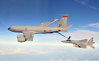 A US Air Force Boeing stratotanker refueling a fighter jet mid-air.