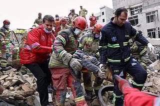 Rescue workers carry a severely injured man after pulling him from the rubble following a strike in southern Tehran, Iran, Friday, March 13, 2026. (AP Photo/Sajjad Safari)