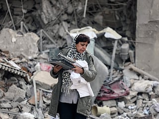 A Iranian woman collects belongings from the rubble of a destroyed residential building in Tehran on March 12, 2026. 