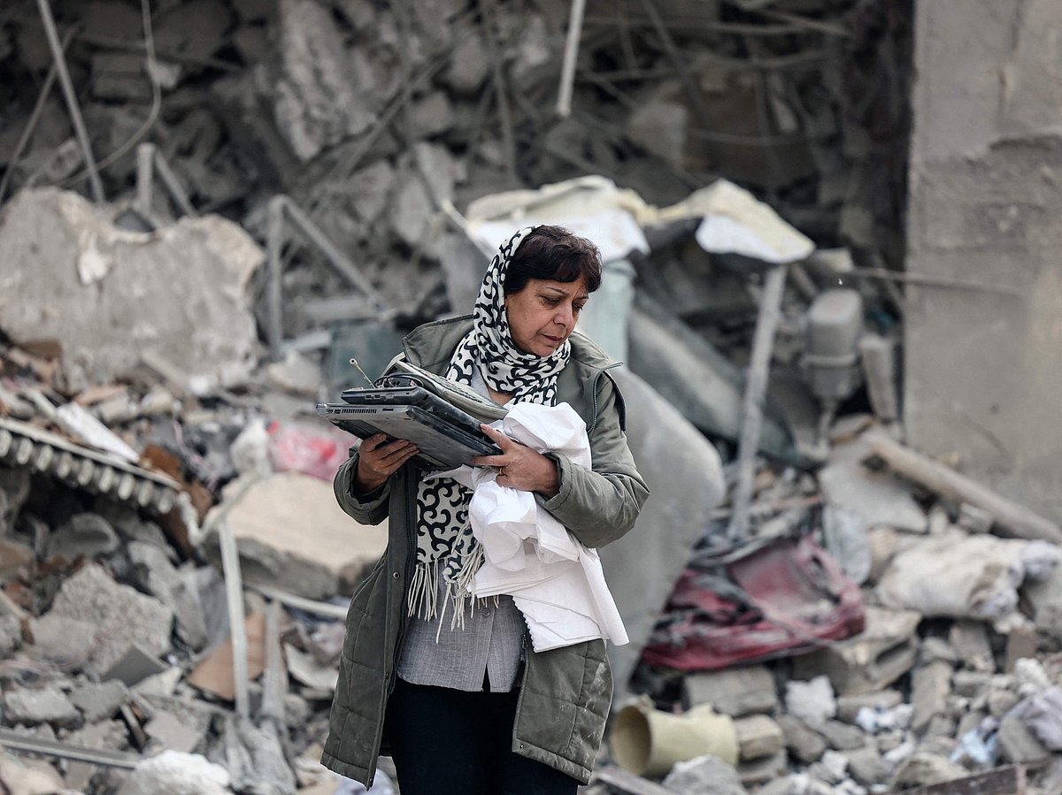 A Iranian woman collects belongings from the rubble of a destroyed residential building in Tehran on March 12, 2026. 