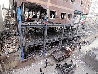 Iranian workers clear the debris from a building damaged in US-Israel attack in Tehran on March 15, 2026. 