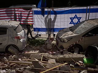 Israeli authorities hang Israeli and US flags at the site struck by an Iranian missile that killed two people, in Ramat Gan, Israel, Wednesday, March 18, 2026. 