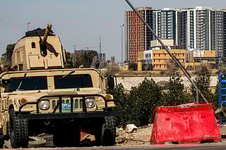 An Iraqi army armoured humvee vehicle is deployed near the banks of the Tigris River to protect the US Embassy headquarters (R) in Baghdad's fortified "Green Zone" on March 18, 2026.