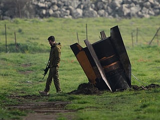 An Israeli soldier stands next to a fragment of a missile fired from Iran and intercepted by Israeli air defence system embedded in an open field in the Israeli-controlled Golan Heights. 