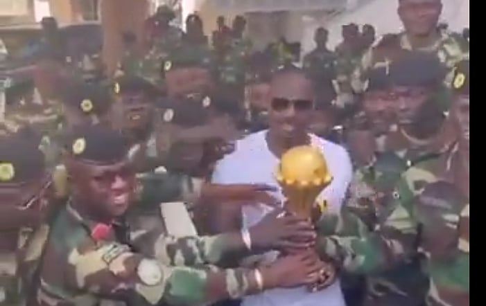 Senegal coach at a military facility with the AfCON trophy