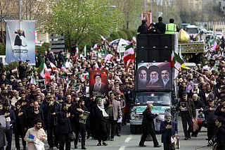 A hearse decorated with pictures of Iranian spiritual leader Ayatollah Ruhollah Khomeini, Iran's slain supreme leader Ayatollah Ali Khamenei and Iran's new Supreme Leader Ayatollah Mojtaba Khamenei drives past Iranians attending the funeral ceremony of Iran's Revolutionary Guards spokesperson Ali Mohammad Naini, who was killed in US-Israeli strikes, in Tehran on March 21, 2026.  