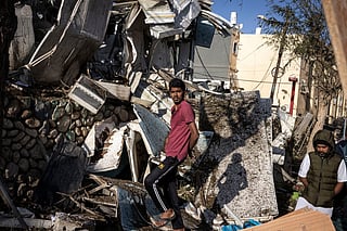 People inspect the site of an Iranian missile strike in Dimona on March 22, 2026.