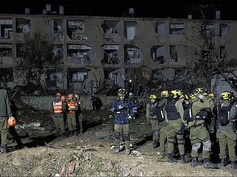 This frame grab from AFPTV footage shows first responders inspecting the site of an Iranian missile strike in Dimona on March 21, 2026. Two Iranian missiles struck southern Israel on March 21, injuring more than 100 people in the most destructive attack of the three-week war, with Prime Minister Benjamin Netanyahu vowing to retaliate "on all fronts". 