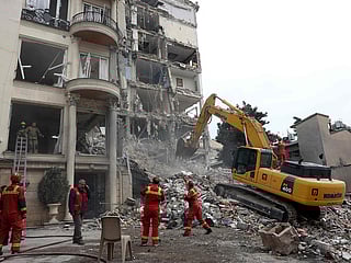 Iranian firefighters with the help of an excavator clear rubble from a destroyed residential building in northern Tehran on March 23, 2026. 